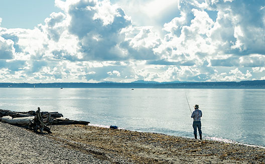 man fishing by the water at Golden Gardens Park