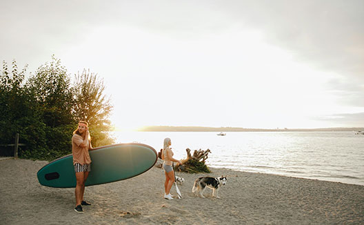 man, woman and dog preparing to paddle board on the water
